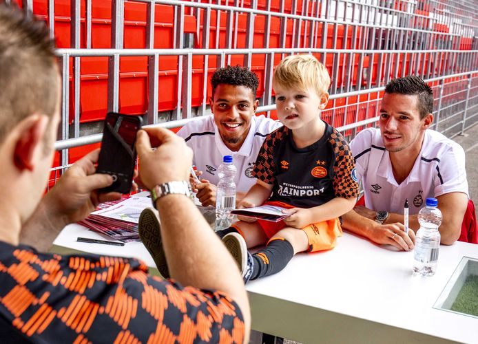 Donyell Malen en Nick Viergever gaan met een jonge supporter van PSV op de foto.