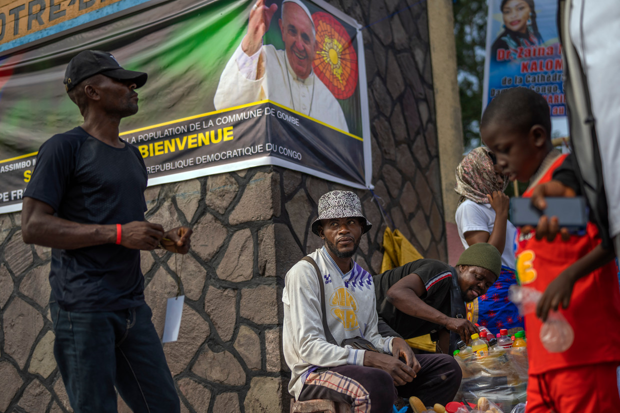 Handelaars in Kinshasa voor een spandoek die de paus alvast verwelkomt. Beeld AP
