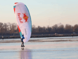 Schaatsende paraglider zweeft over het ijs in Friesland
