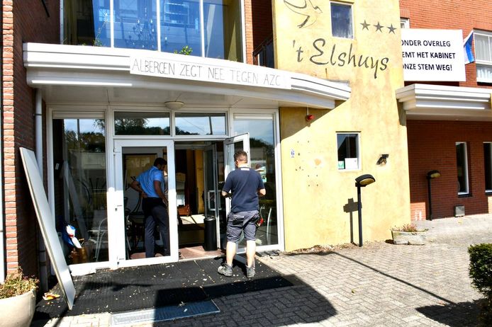 Diverse lieden nemen de schade op (en gaan die repareren) bij het voormalige hotel ’t Elshuys in Albergen. De nacht ervoor is het beoogde asielzoekerscentrum bekogeld met maiskolven. Daarbij sneuvelde een ruit in de toegangsdeur.