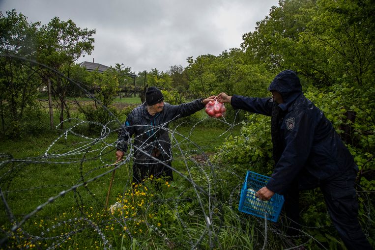 Georgische grenspolitie overhandigt voedsel over een prikkeldraadomheining aan een boer. Beeld Getty Images