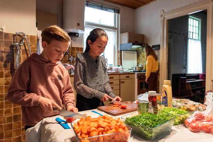Senne en Merel snijden samen de tomaten terwijl Lilly de pannen in de gaten doet houden.