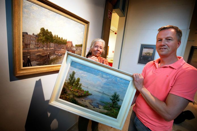 Marijke Ravenswaaij-Deege en Mathieu van Pelt houden samen het riviergezicht op Woudrichem vast. Naast hen hangt een impressie van de Lingehaven van H.A. Ravenswaaij.