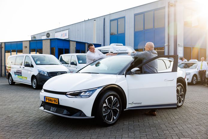Medewerkers van Taxi Korthout bevestigen het taxiplaatje op een splinternieuwe elektrische taxi.