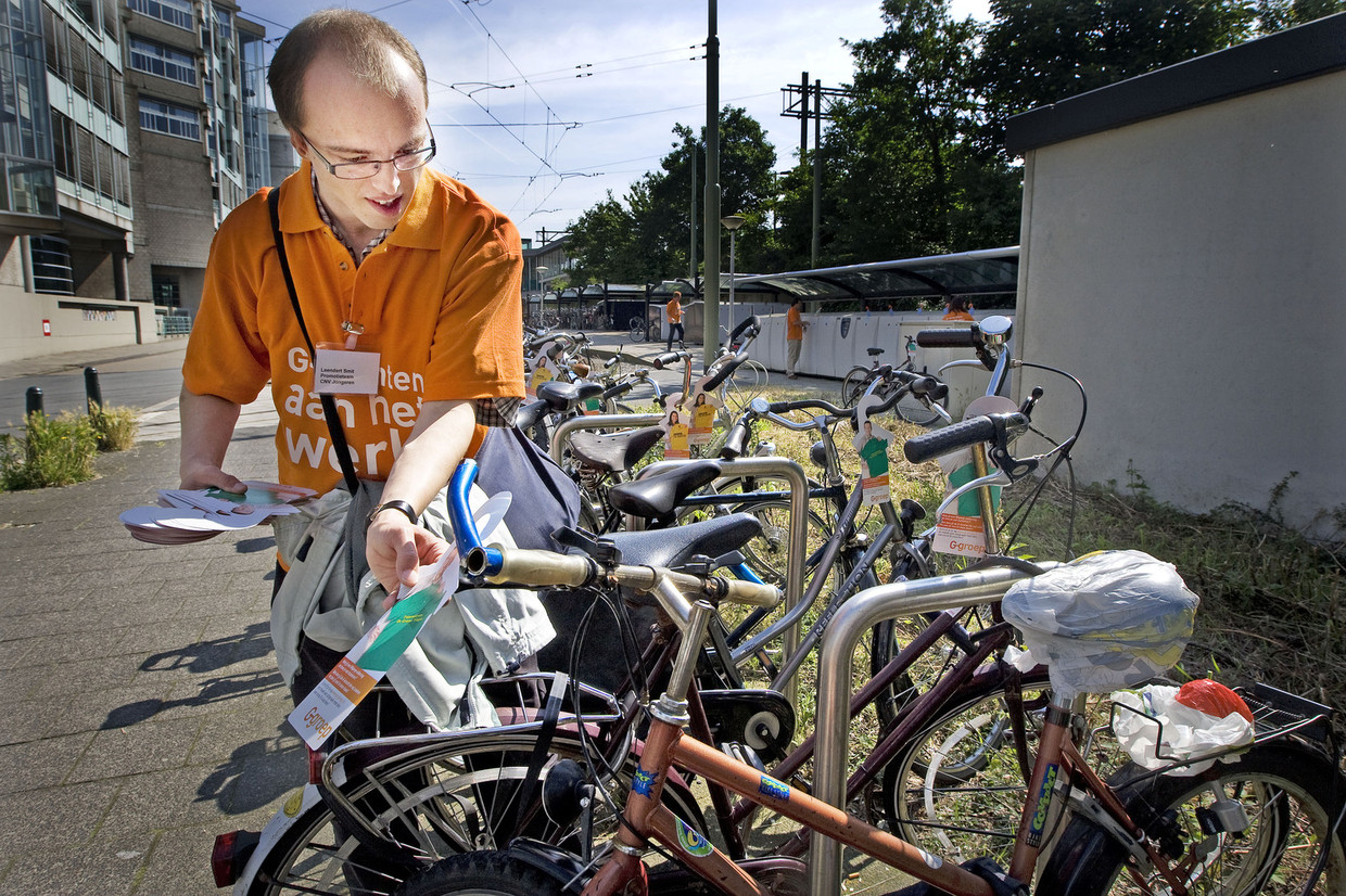 Een wajonger hangt flyers op aan fietsen om actie te voeren voor banen voor jonggehandicapten. Beeld anp