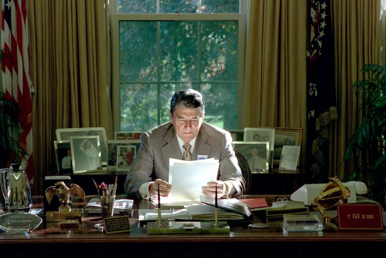 President Reagan  in The Oval Office, 26 oktober 1988. Rechtsonder het bordje met de tekst ,,It can be done”.  Beeld National Archive