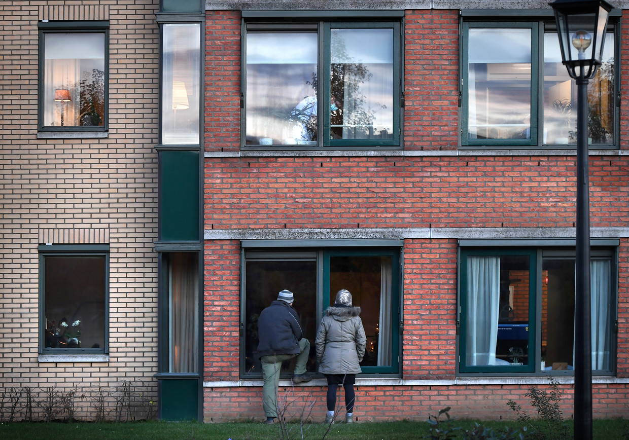 Een bewoner van zorgcentrum Anker krijgt bezoek, dat veilig buiten blijft staan. Beeld Marcel van den Bergh / de Volkskrant