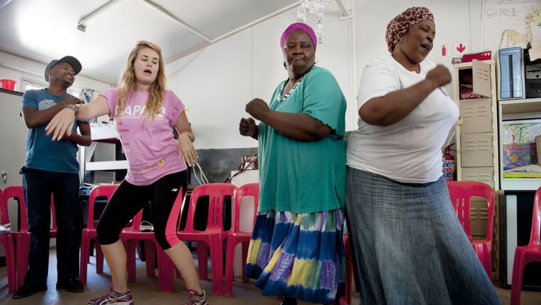 Een vrijwilliger danst met twee 'Grandmothers Against Poverty and Aids' in Kaapstad. Beeld An-Sofie Kesteleyn