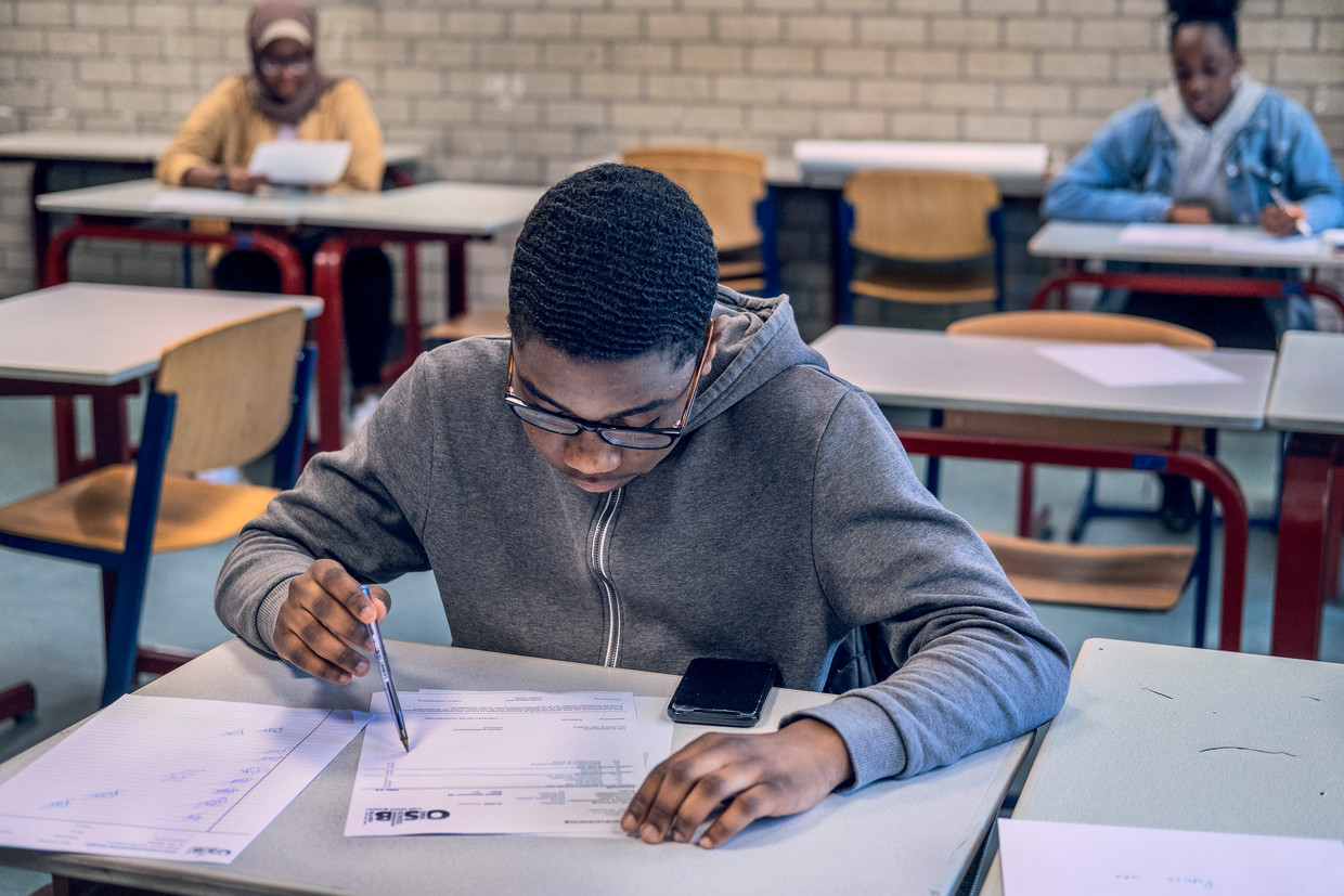 Patrick (15) is geslaagd en tekent zijn cijferlijst op de Openbare Schoolgemeenschap Bijlmer in Amsterdam. 