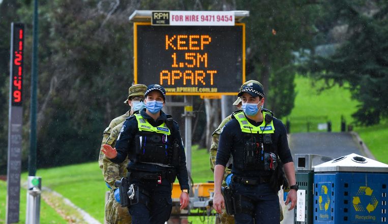Politie in Melbourne bij een groot bord dat oproept tot 1,5 meter afstand te houden. Beeld AFP
