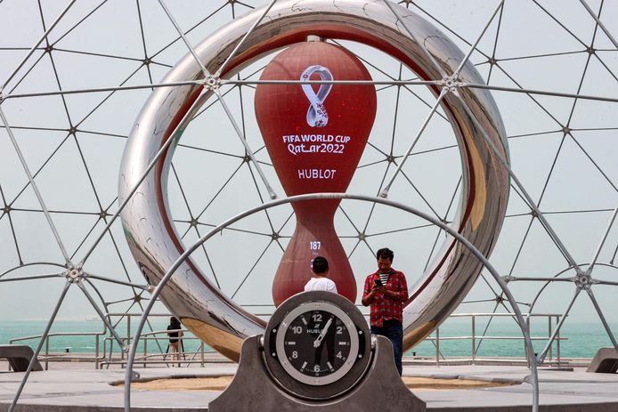Mensen staan in Doha bij een klok die aftelt naar het WK voetbal in Qatar.