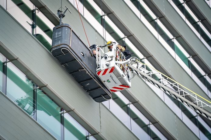 De glazenwassers kwamen met hulp van de brandweer weer veilig op de grond terecht.