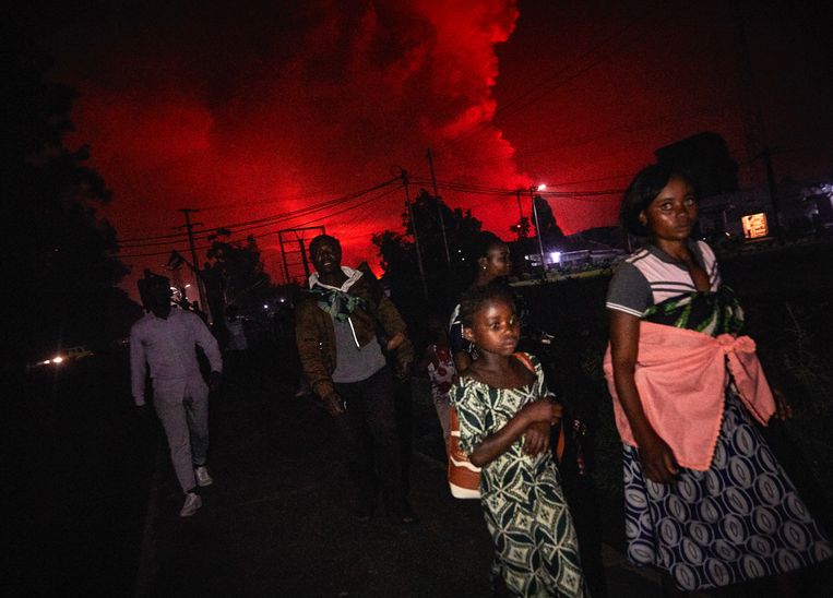 Inwoners van Goma vluchten. Op de achtergrond is de uitbarsting te zien. Beeld EPA