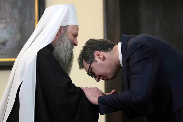 Servisch president Aleksandar Vučić kust de hand van patriarch Porfirije. Beeld AP