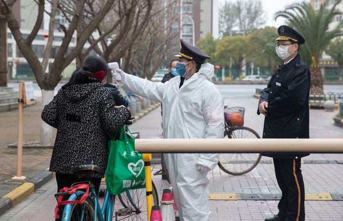 Een veiligheidsagent controleert de temperatuur van een inwoner van Wuhan, het epicentrum van de corona-uitbraak in China.
