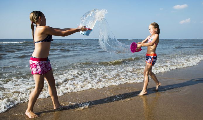 Kinderen spelen met water op het strand van Zandvoort.