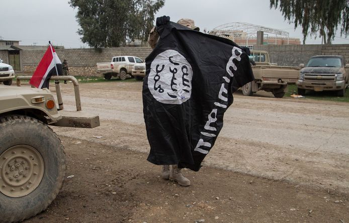 Een Iraakse militair toont een vlag van terreurorganisatie Islamitische Staat.