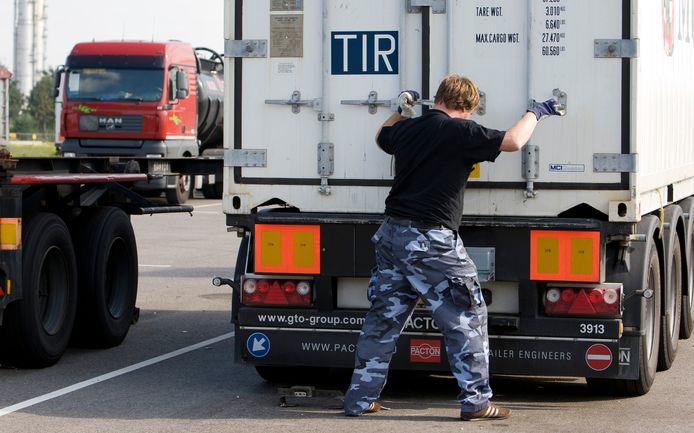 Een chauffeur sluit en verzegeld de laadklep van een container achterop zijn wagen.