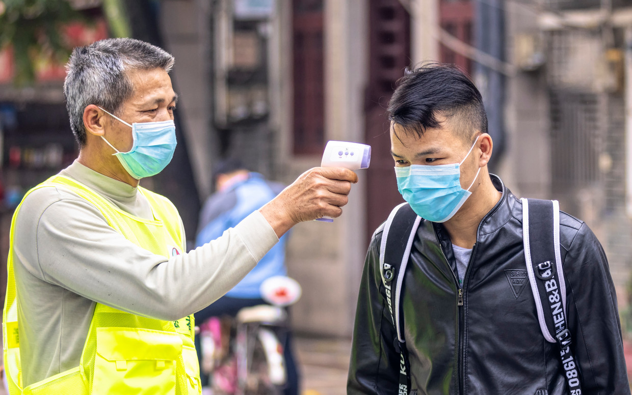 Een man wordt gecontroleerd op zijn lichaamstemperatuur in Guangzhou, China. Beeld EPA