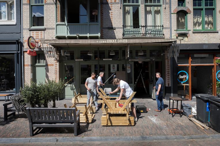 Jos de Winter (rechts), eigenaar van café Nieuwe Dikke Dries, kijkt naar zijn terras terwijl personeel de tafels schildert.  Beeld Werry Crone