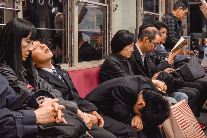 Japanse werknemers in Hiroshima doen een dutje in het openbaar vervoer.