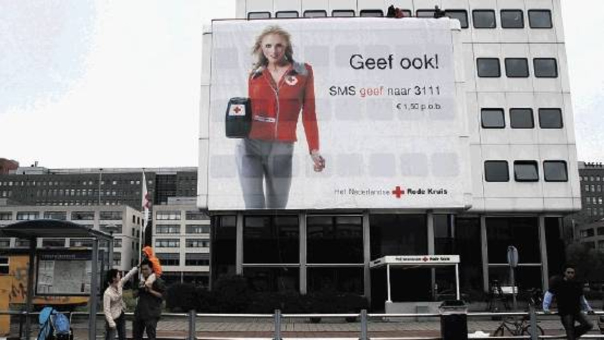 Aan de gevel van het hoofdkantoor in Den Haag roept topmodel Yfke Sturm namens het Rode Kruis mensen op om geld te doneren. (ROBERT VAN WILLIGENBURG, ANP) Beeld 