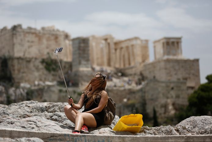 Een toeriste neemt een selfie voor de Akropolis in Athene.