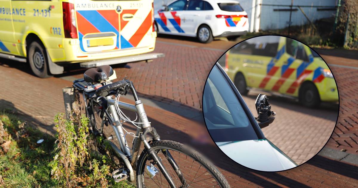 Fietser gaat onderuit na botsing met autospiegel en raakt gewond aan gezicht.