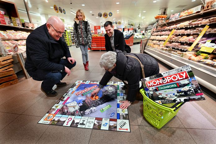 Culemborger Hans van Diejen speelt met zijn schoonmoeder Marlies Brocatus een potje Culemborgs Monopoly op een groot bord midden in supermarkt PLUS. Op de achtergrond eigenaar Giel Smits.