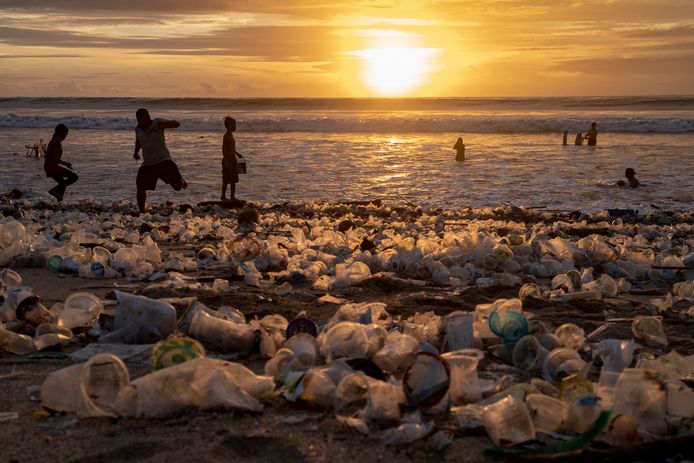 Zonsondergang op Kuta Beach in Bali. Mensen moeten zich een weg banen door plastic.
