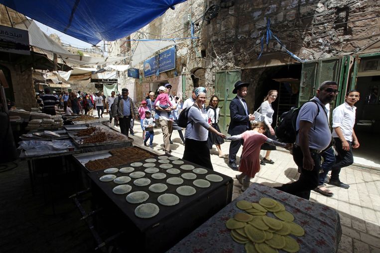 Joodse kolonisten en andere bezoekers lopen over de oude markt in Hebron. Beeld EPA
