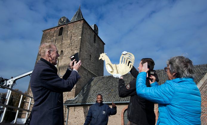 Henk de Haan (links) legt de terug te plaatsen torenhaan van de kerk van Dodewaard van dichtbij vast voor het nageslacht.