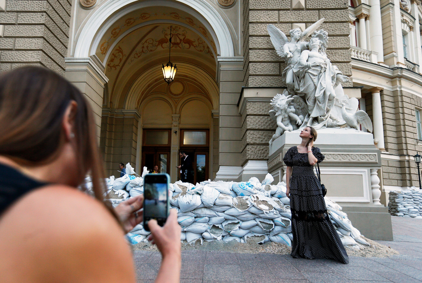 Een vrouw poseert voor het operatheater in Odessa. Monumenten worden onder meer beschermd met zandzakken.