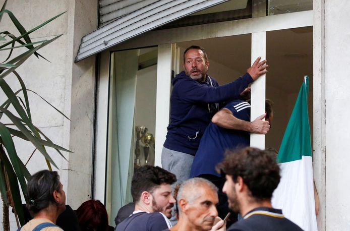 Demonstranten klimmen door een raam van het hoofdkwartier van de Italiaanse vakbond CGIL tijdens de protesten.