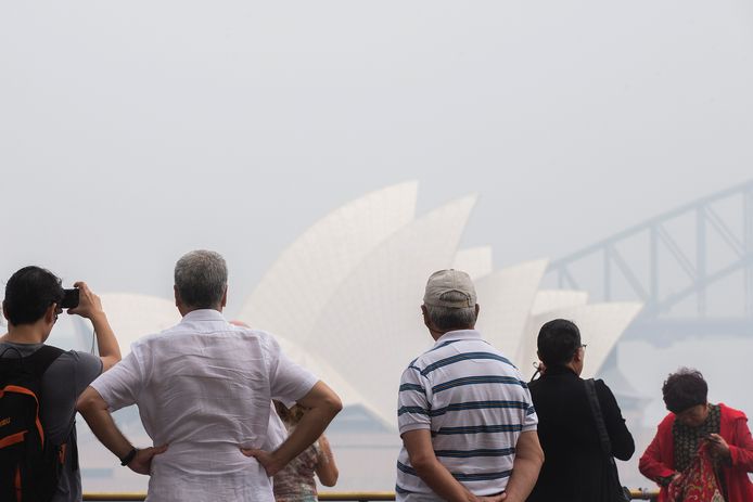 Archiefbeeld. Toeristen voor het operagebouw in Sydney. Door de rook van de vele bosbranden was de luchtkwaliteit er de afgelopen weken bijzonder slecht.