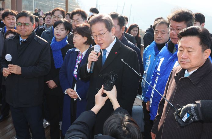 De Zuid-Koreaanse oppositieleider Lee Jae-myung (midden) praat met verslaggevers tijdens zijn bezoek aan een vliegveld in aanbouw in de stad Busan, kort voordat hij wordt aangevallen.