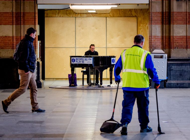 Een voorbijganger speelt op de vleugelpiano in de centrale hal van station Amsterdam Centraal. Beeld ANP