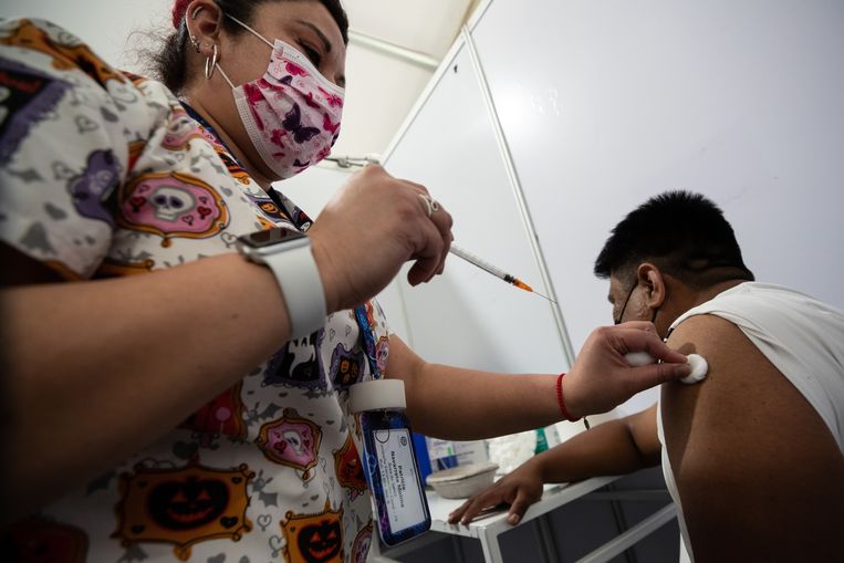 Een verpleegster in Santiago dient een boosterprik toe. Er stonden donderdag lange rijen voor de vaccinatiecentra in de Chileense hoofdstad. Veel mensen halen een extra prik. Op sommige locaties liep de wachttijd op tot drie uur. Beeld EPA