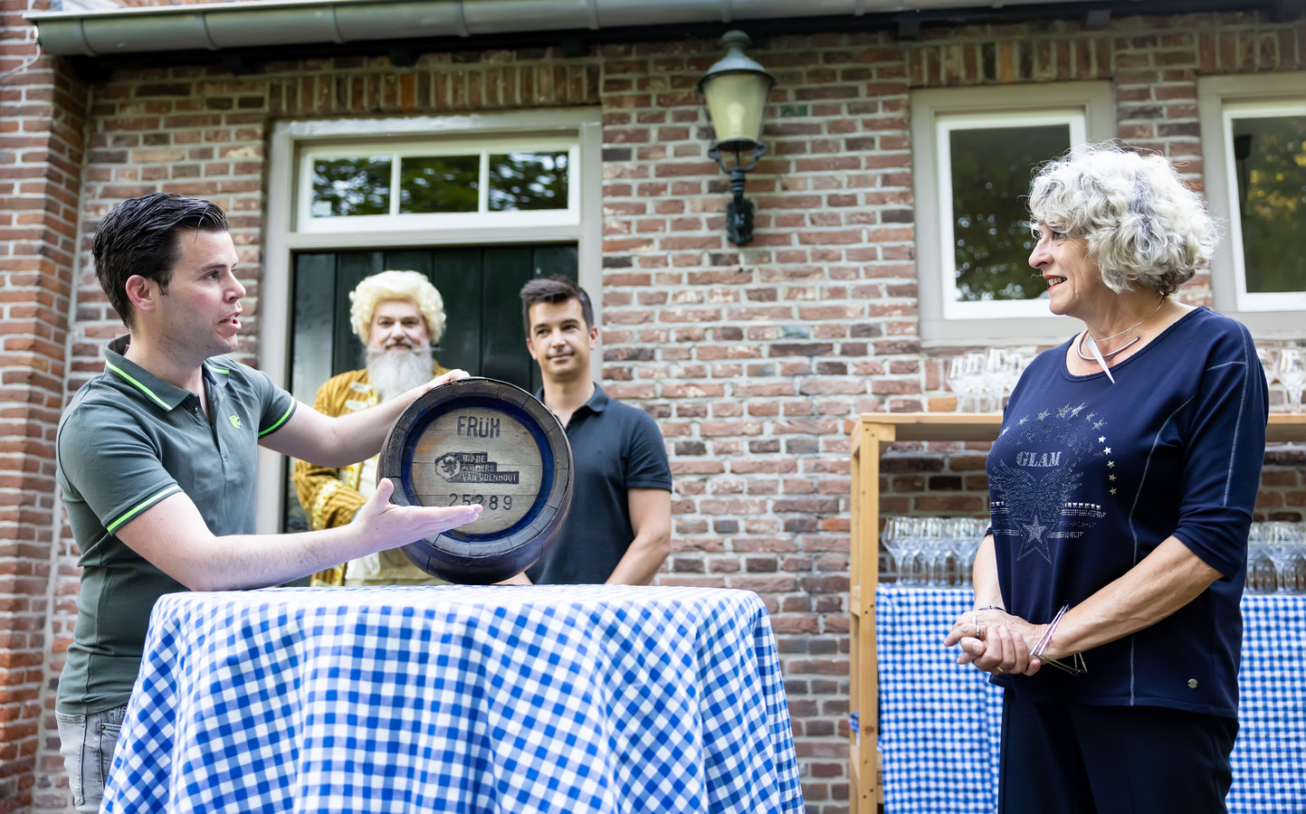 In Udenhout, bij kasteel Strijhoef werd het nieuw Udenhouts bier gepresenteerd. Stefan Ammerlaan (links) reikt het eerste vaatje uit aan Wilma de Jong, de nieuwe voorzitter van de dorpsraad. Koen Verbunt, naast De Jong, is de andere initiatiefnemer.