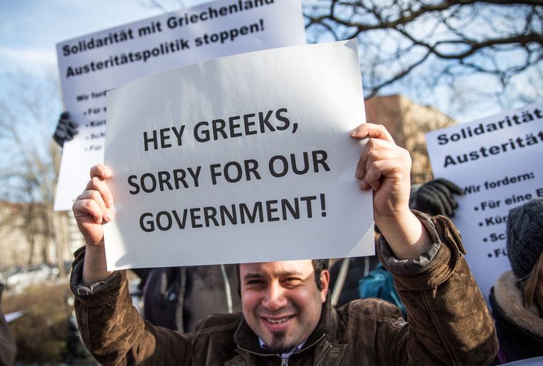 epa04604330 A protester holds a placard that reads 'Hey Greeks, sorry for our Government!' in front of the German Ministry of Finance in Berlin, Germany, 05 February 2015. The meeting between Varoufakis and Schaeuble comes after the European Central Bank (ECB) decided to turn up the pressure on Greece over its vow to renegotiate the terms of its bailout by refusing to accept Greek government bonds as security for loans.  EPA/MICHAEL KAPPELER Beeld EPA