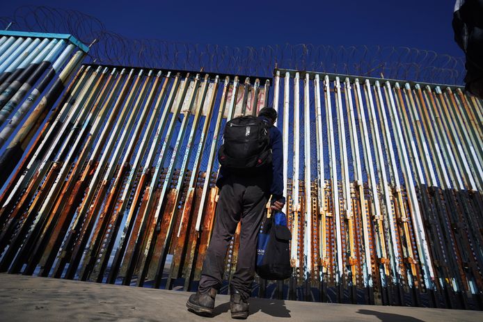 Een migrant wacht aan de Mexicaanse kant van de grens tussen de VS en Mexico in Tijuna, Mexico.