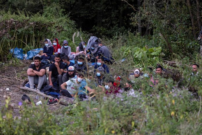 Een groep vluchtelingen zit op de grond in een veld in de buurt van het kleine Poolse dorp Usnarz Gorny aan de grens met Wit-Rusland. (Foto 20 augustus 2021)