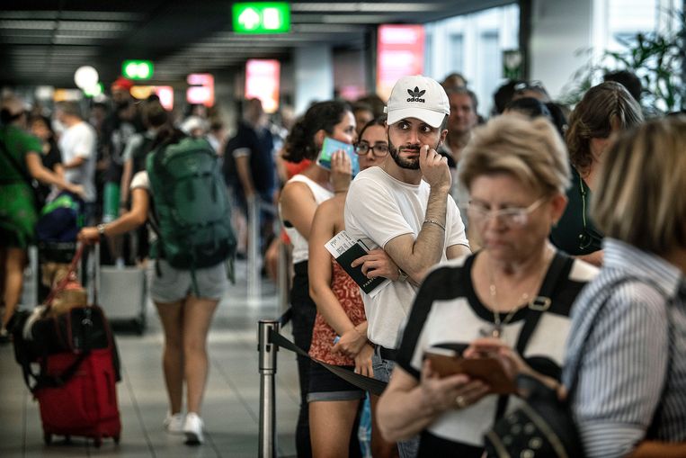 Reizigers balen op Schiphol. Door een storing in de kerosinetoevoer kunnen veel vluchten niet vertrekken of alleen met veel vertraging. Lange rijen wachtenden dus op de overvolle luchthaven. Beeld Guus Dubbelman / de Volkskrant