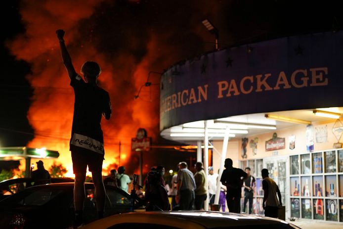 Demonstranten kijken toe terwijl het restaurant waar het incident plaatsvond in vlammen opgaat.