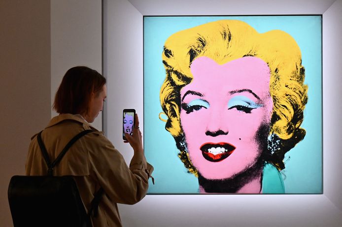 Een vrouw maakt een foto van Andy Warhols 'Shot Sage Blue Marilyn’ bij veilinghuis Christie's.