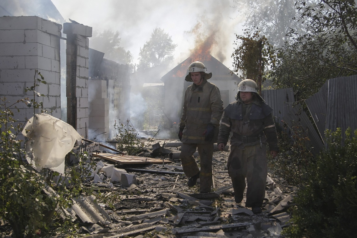 Brandweermannen lopen langs beschadigde gebouwen nabij het vliegveld in Donetsk, waar de afgelopen dagen hevig is gevochten. Beeld epa