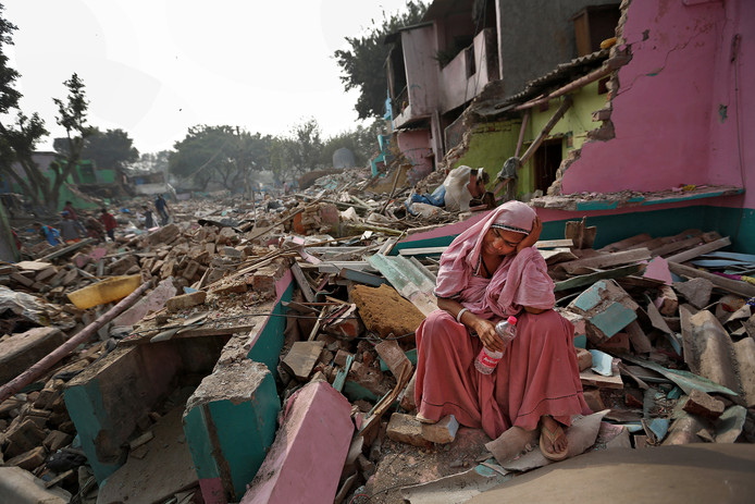 Een Indiase vrouw zit bij de pakken neer te midden van wat eens haar huis was. De sloppenwijk is door de lokale overheid plat gegooid in een poging de bewoners uit Delhi te laten te vertrekken. Foto Cathal McNaughton