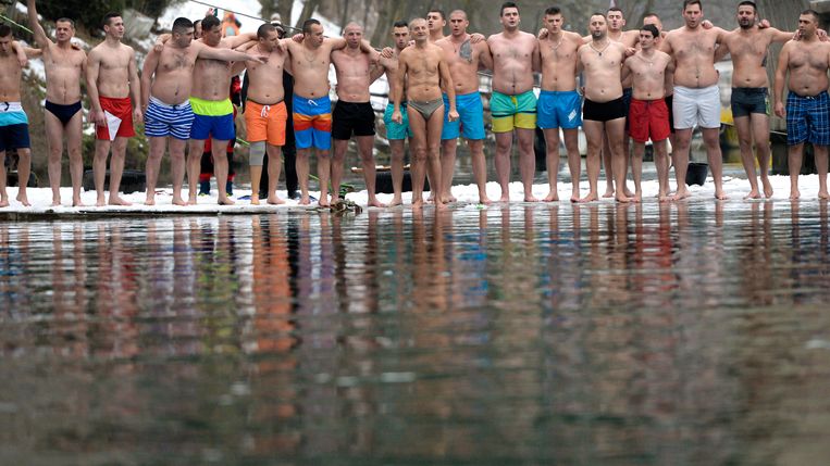 In Visegrad, Bosnië staan mannen klaar voor een duik in het ijskoude water van rivier Drina om een houten kruis naar boven te halen. Leden van de Servische orthodoxe kerk gingen gisteren het water in ter gelegenheid van de viering van de feestdag openbaring met het doel hun zonden weg te wassen. Beeld AP