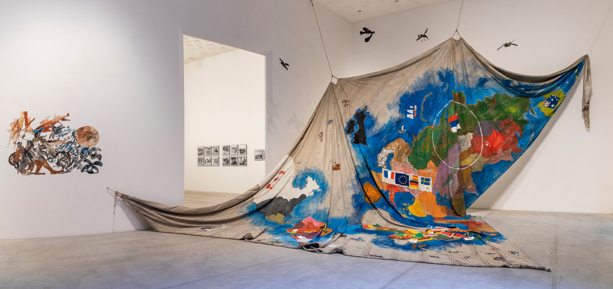 Een groot beschilderd scheepszeil, een werk van Anna Boghiguian in de expo 'Le Déracinement' in het Hasseltse Z33. Beeld Selma Gurbuz