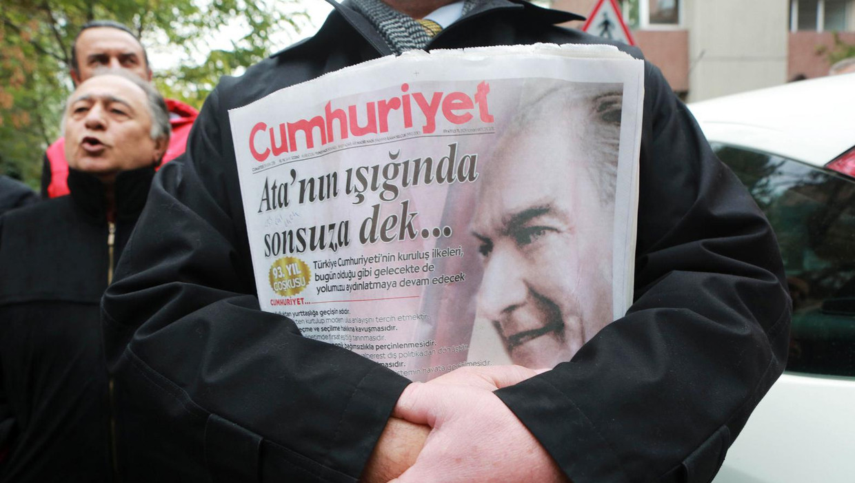 Een Turkse man houdt een exemplaar van de Cumhuriyet vast tijdens een demonstratie tegen de arrestatie van de negen journalisten. Beeld afp
